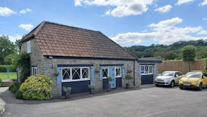 A two-story stone house with a tiled roof, a garage, and two parked cars. - Bluebell House 5 Star Luxury 4 Bdrms and hot tub (Somerton)