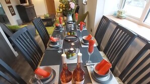 A dining area with a long table set for six, featuring candles, wine bottles, and a vase with flowers. - Bluebell House 5 Star Luxury 4 Bdrms and hot tub (Somerton)