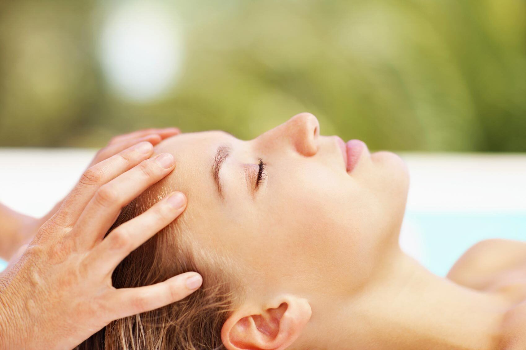 A person receiving a head massage by another individual.