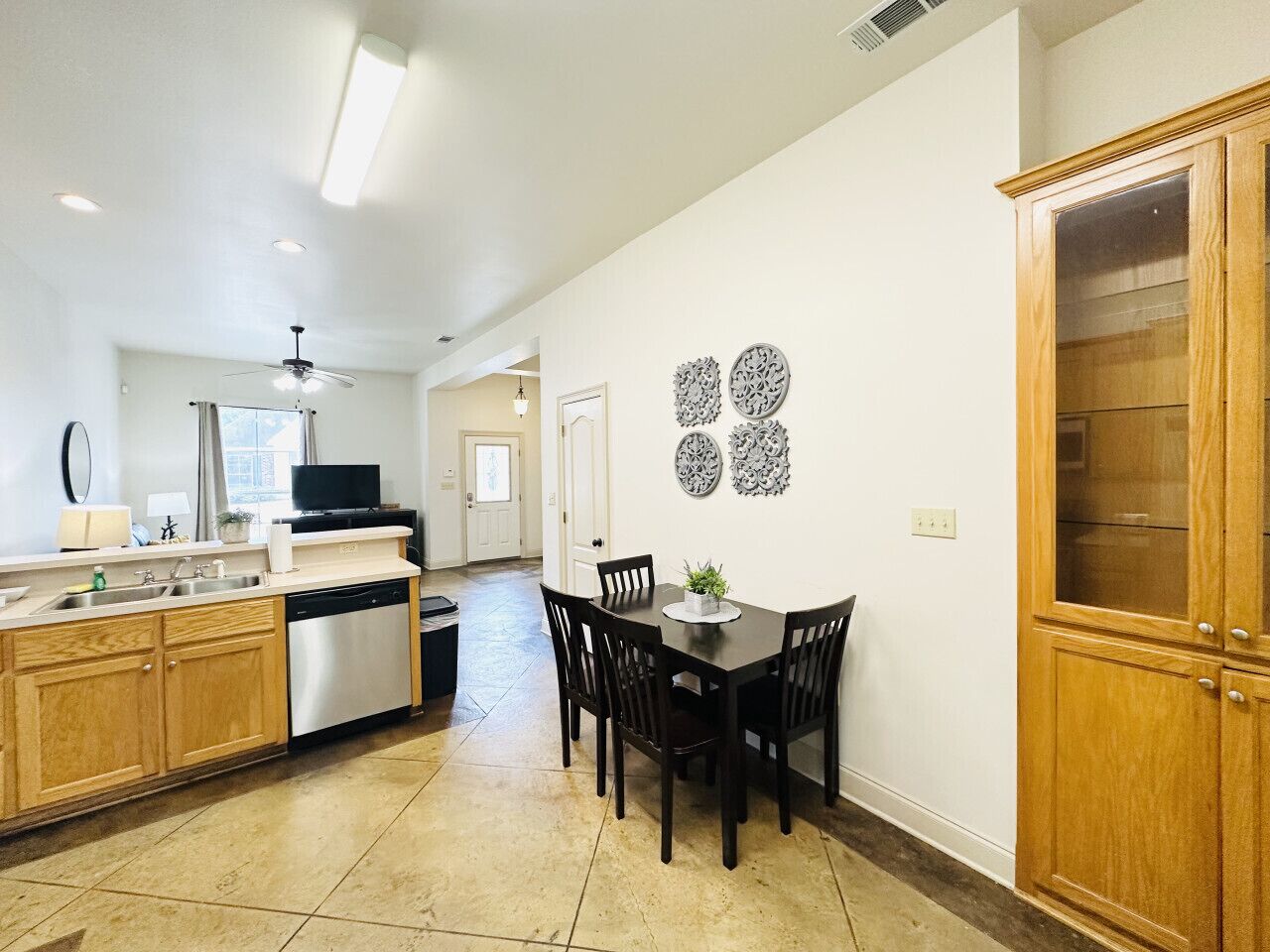 A kitchen with wooden cabinets, a dining table with chairs, and a television on the counter.