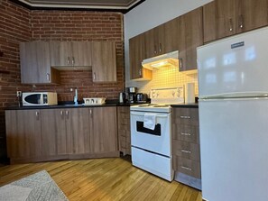 Une cuisine avec des meubles en bois, un four à micro-ondes, un four traditionnel et un réfrigérateur.