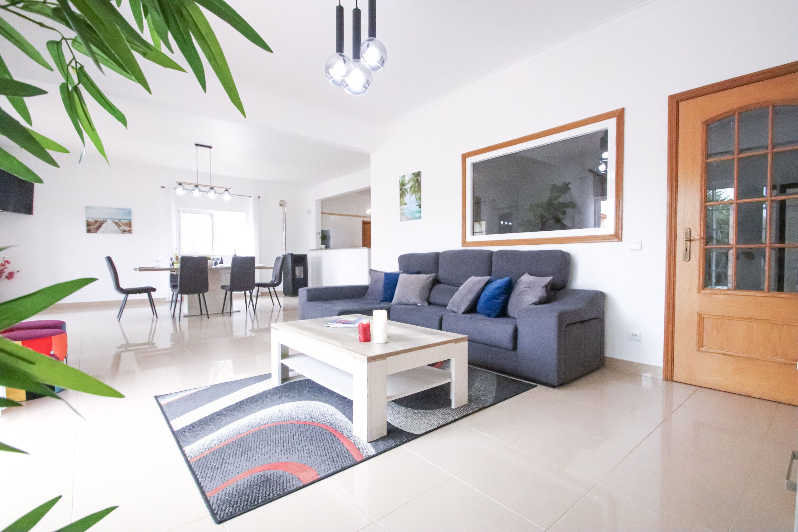 Una sala moderna con un sofá gris, una mesita de centro blanca y un comedor con sillas y una mesa.