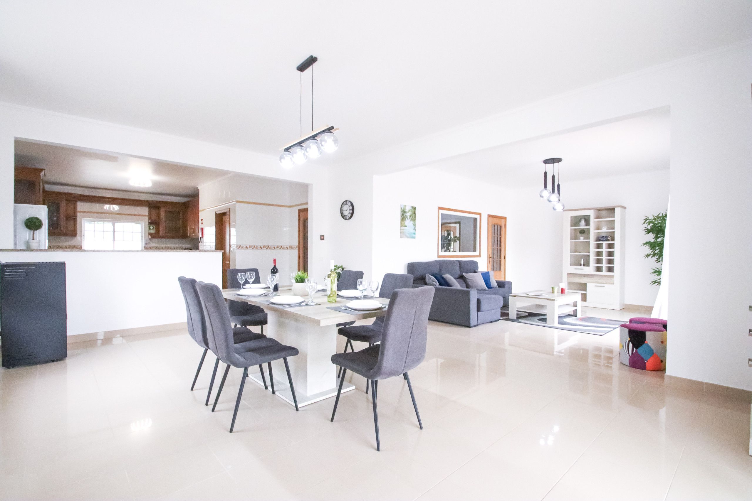 Una cocina moderna con refrigerador, una mesa de comedor con sillas y una sala de estar con sofá y mesa de centro.