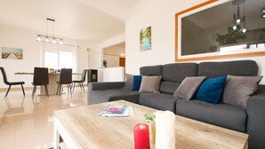 A modern living room with a grey sofa, a wooden coffee table, and a red candle. - Villa with Saltwater Swimming Pool (Albufeira)