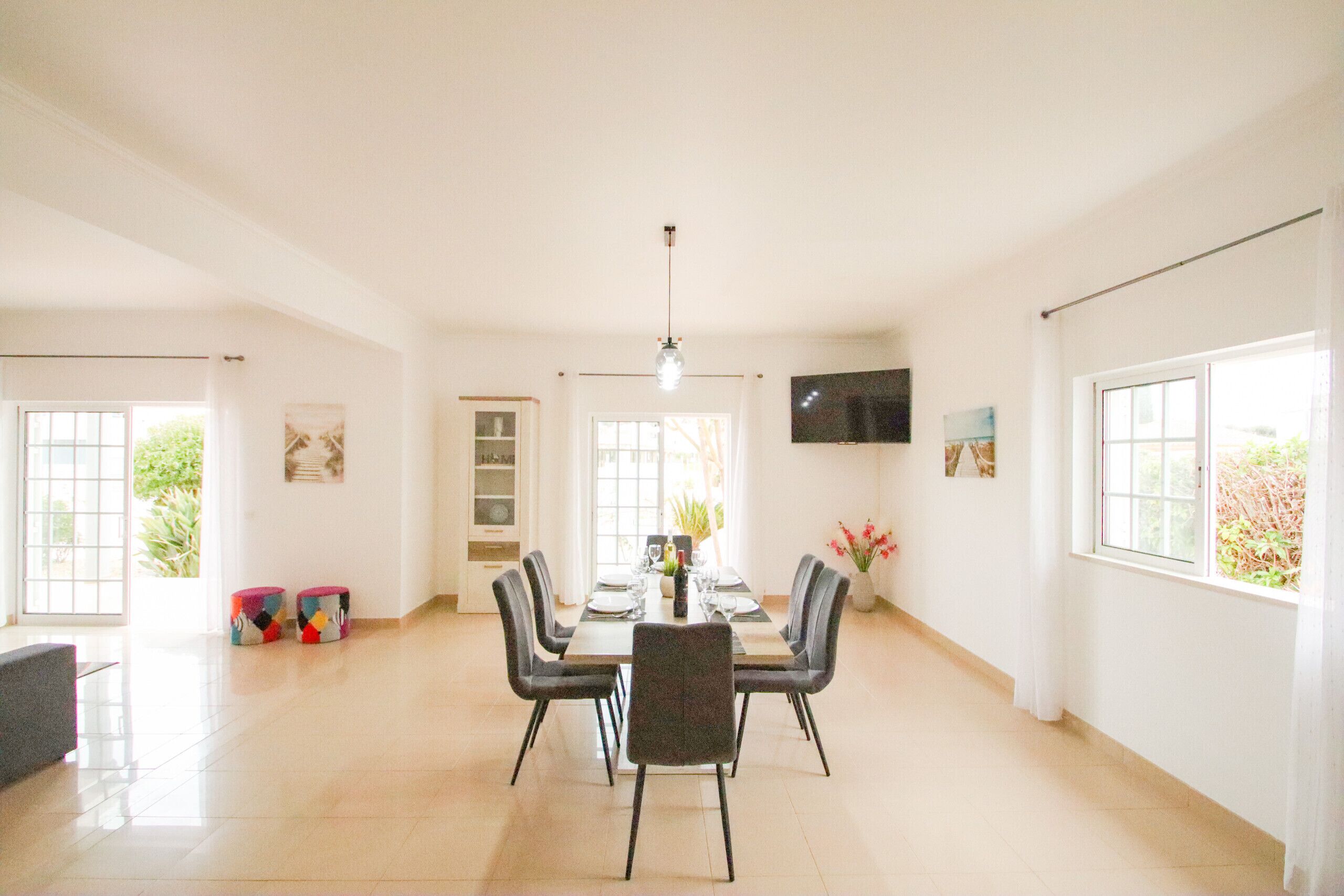 A spacious dining area with a long table, chairs, and a television on the wall.