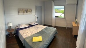 Una camera da letto con un letto, un comodino, una lampada, una finestra con tende e una porta.