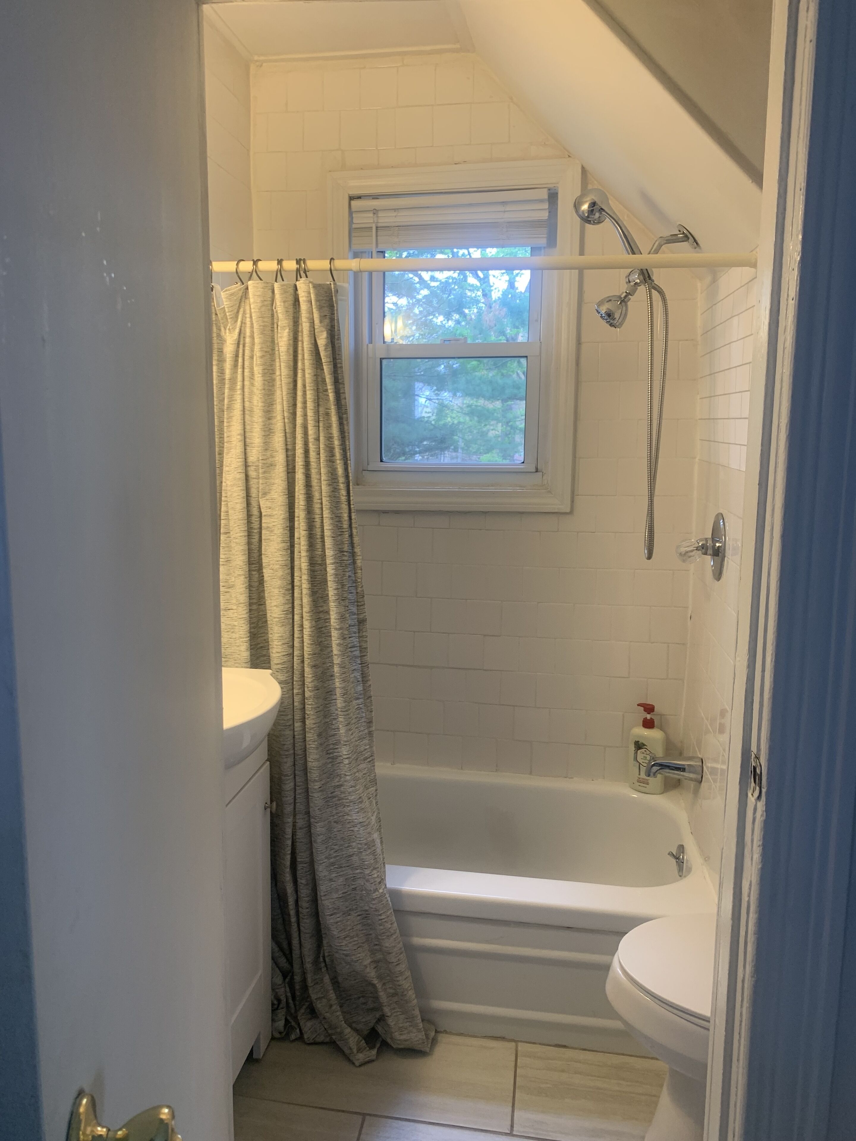 Een badkamer met een bad, een raam en een toilet.