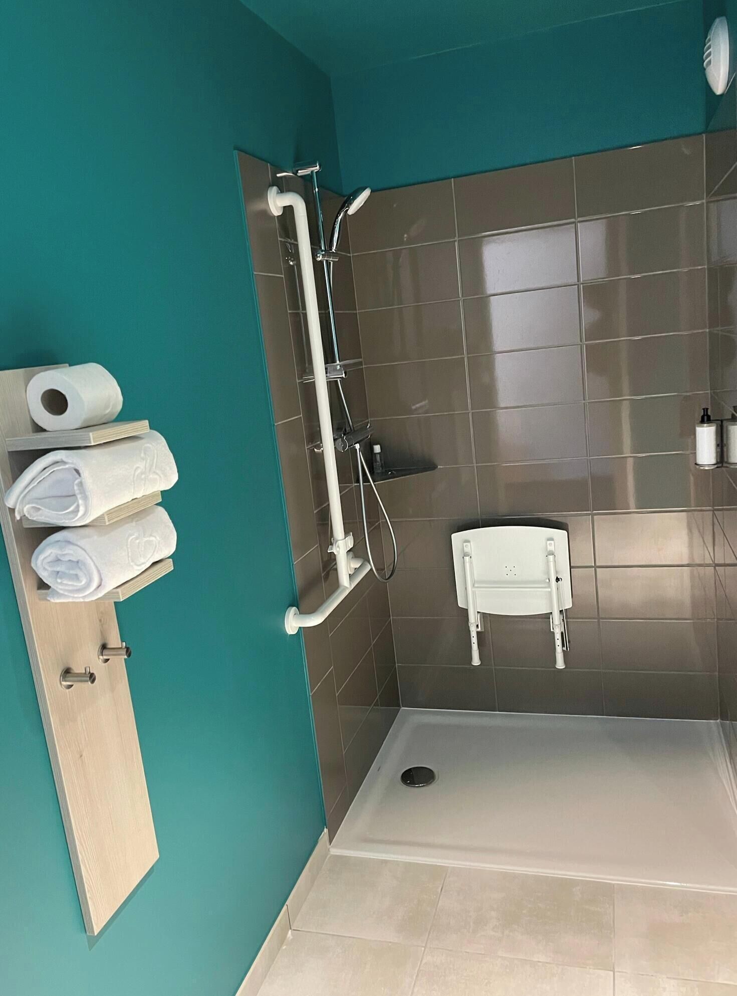 Une salle de bain moderne équipée d’une douche, de toilettes et d’un porte-serviettes avec des serviettes.