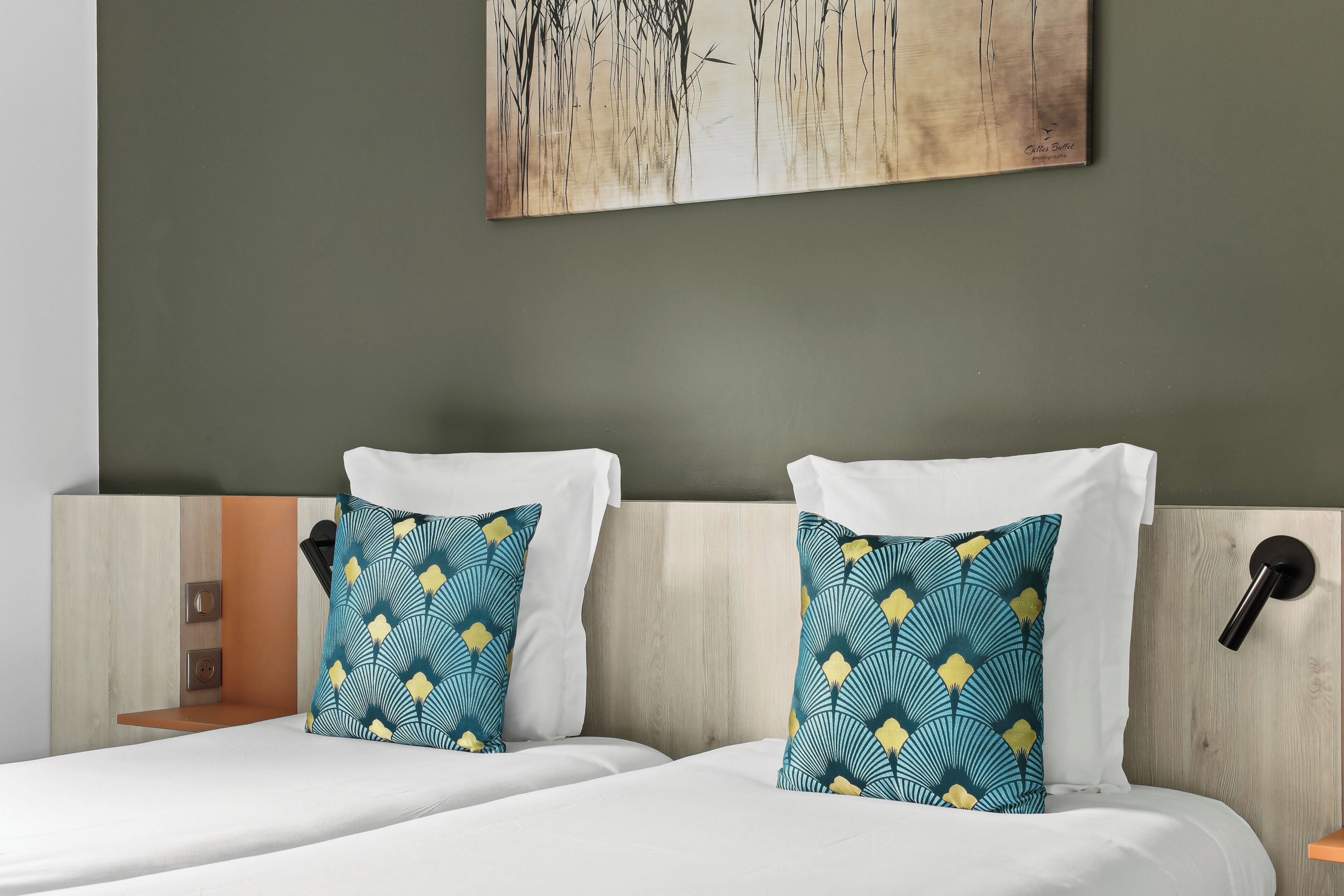 Een hotelkamer met twee bedden, elk voorzien van witte lakens en gestreepte kussens.