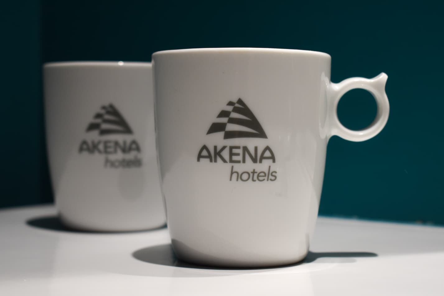 Twee witte bekers met het logo van Akena hotels.