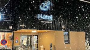 Un hotel con un letrero que dice 'Hotel La BROCATELLE' bajo un techo cubierto de nieve.