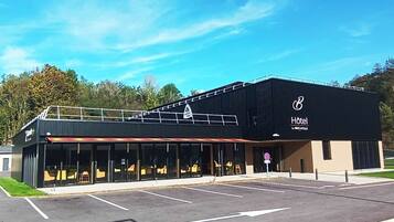 Un hôtel moderne à la façade noire, doté de grandes fenêtres et d’un parking.