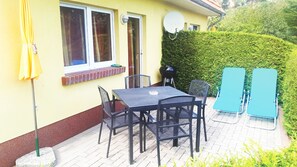Une terrasse avec une table et des chaises, un barbecue et une antenne parabolique.