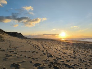 Een strand met voetafdrukken en een ondergaande zon.