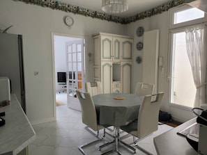 A dining area with a round table, chairs, a clock, and a view of the outdoors.