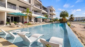 A modern hotel with a pool area, sun loungers, and umbrellas.