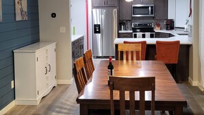 A modern kitchen with stainless steel appliances, a dining area with a wooden table and chairs, and a blue accent wall. - Updated 2bd/2ba. Walk to Village, dog friendly, SHARC passes. (Sunriver)