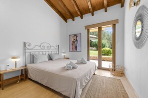 Un dormitorio con cama, lámparas de noche, un cuadro y vistas al jardín.