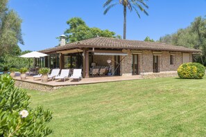 Una casa con patio, mobiliario exterior y fachada de piedra.