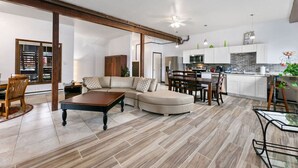 Een moderne woonkamer met een modulaire bank, een houten salontafel en een eethoek met een tafel en stoelen.