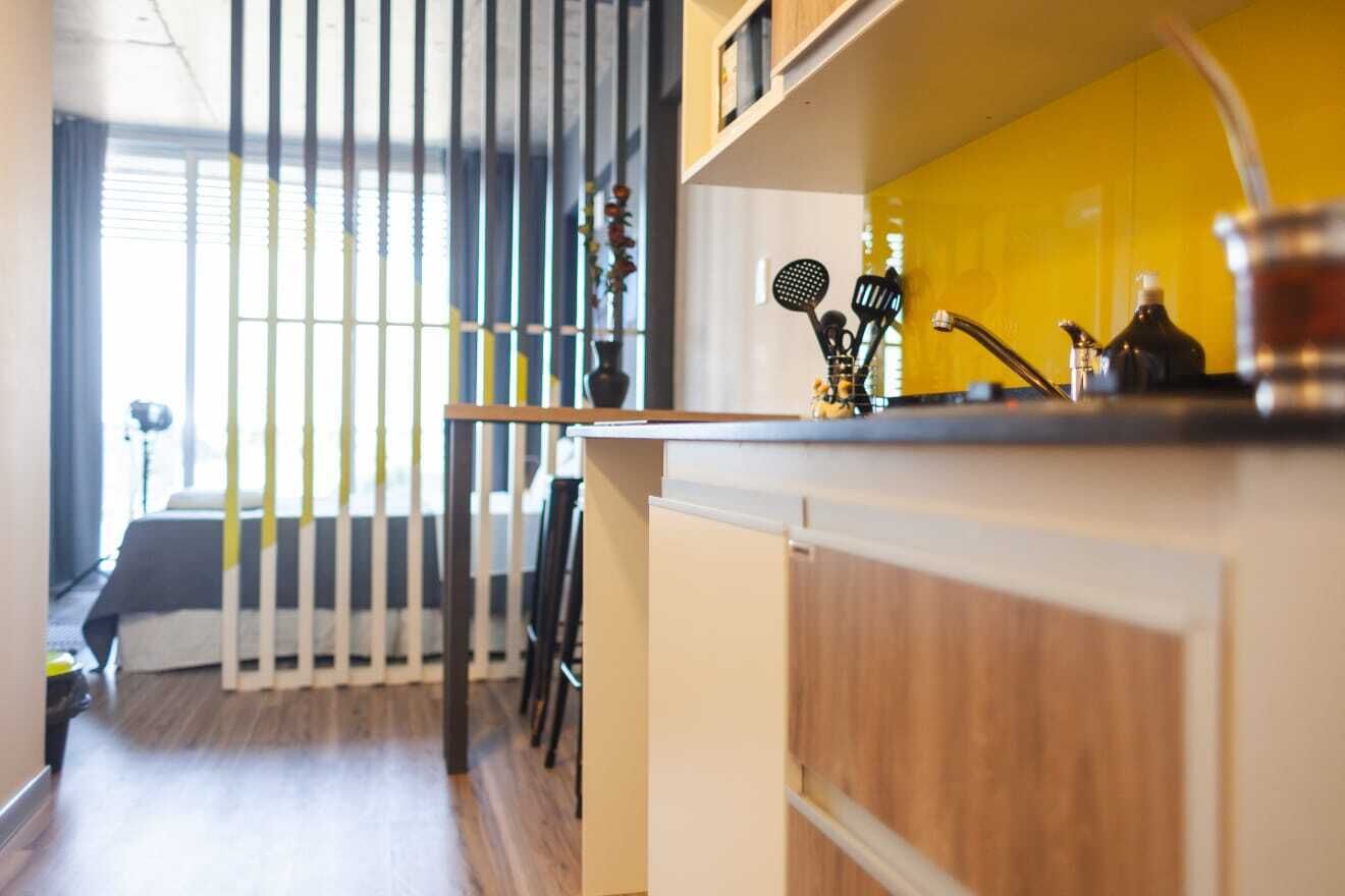 A modern kitchen with a wooden countertop, a yellow backsplash, and various kitchen utensils.