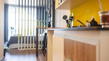 A modern kitchen with a wooden countertop, a yellow backsplash, and various kitchen utensils.