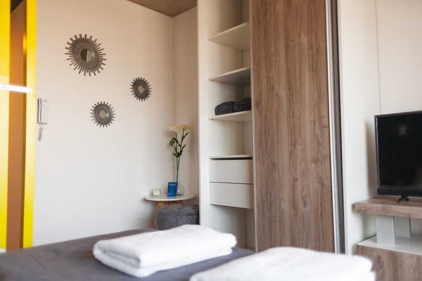 Un dormitorio con cama, televisor, armario y decoración en la pared.