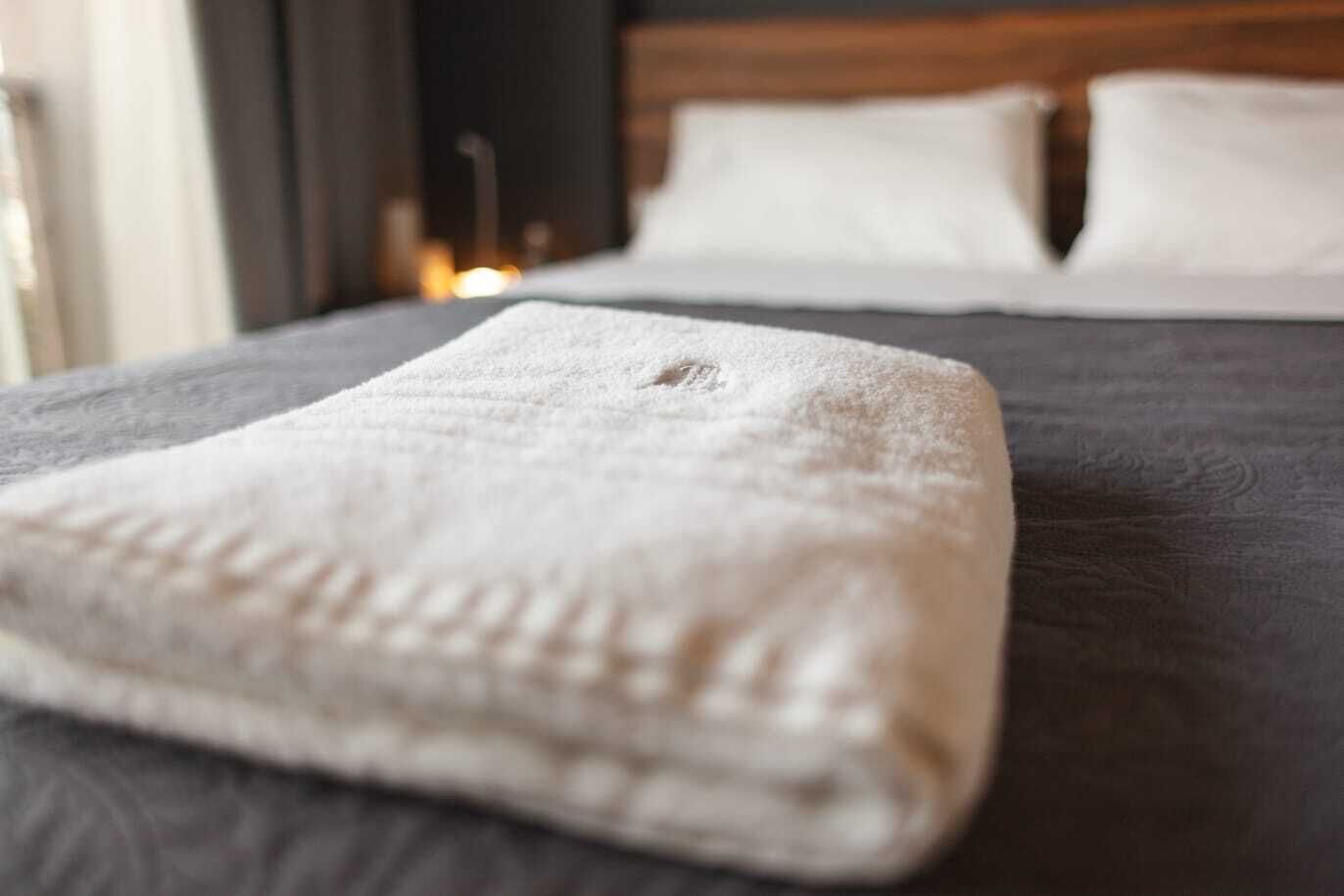 A neatly made bed with a folded white towel on the left side.