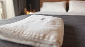 A neatly made bed with a folded white towel on the left side.