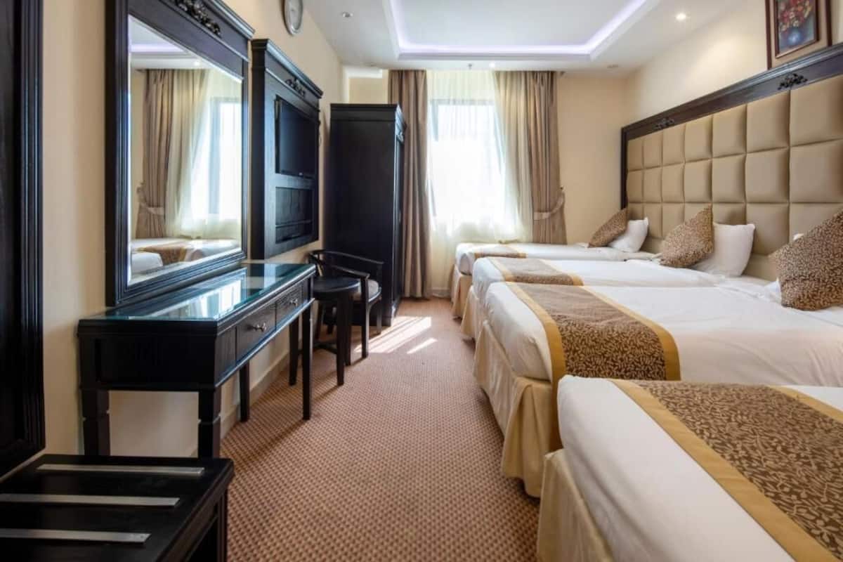 Ein Hotelzimmer mit zwei Betten, einem Schreibtisch mit Stuhl, einem Fernseher und einem großen Spiegel.
