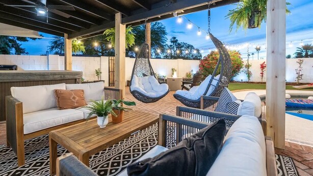 An outdoor patio with a sofa, hanging chairs, and a pool. - WOW! Luxury Desert Oasis! (Mesa)