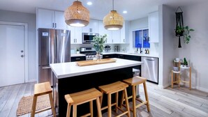 A modern kitchen with a large island, stainless steel appliances, and wooden stools. - WOW! Luxury Desert Oasis! (Mesa)