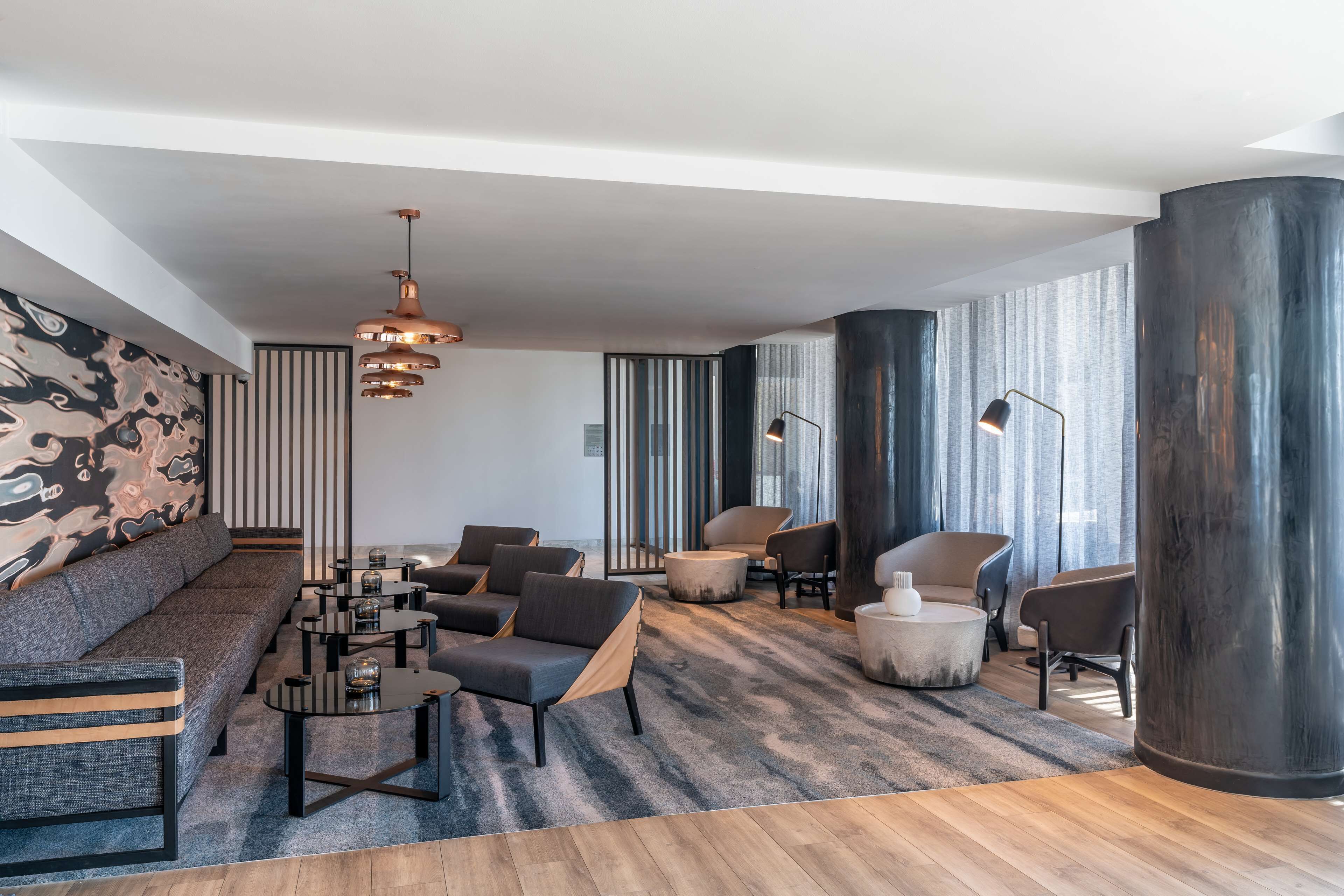 Un salon moderne comprenant un canapé, plusieurs fauteuils, une table basse et une grande colonne.