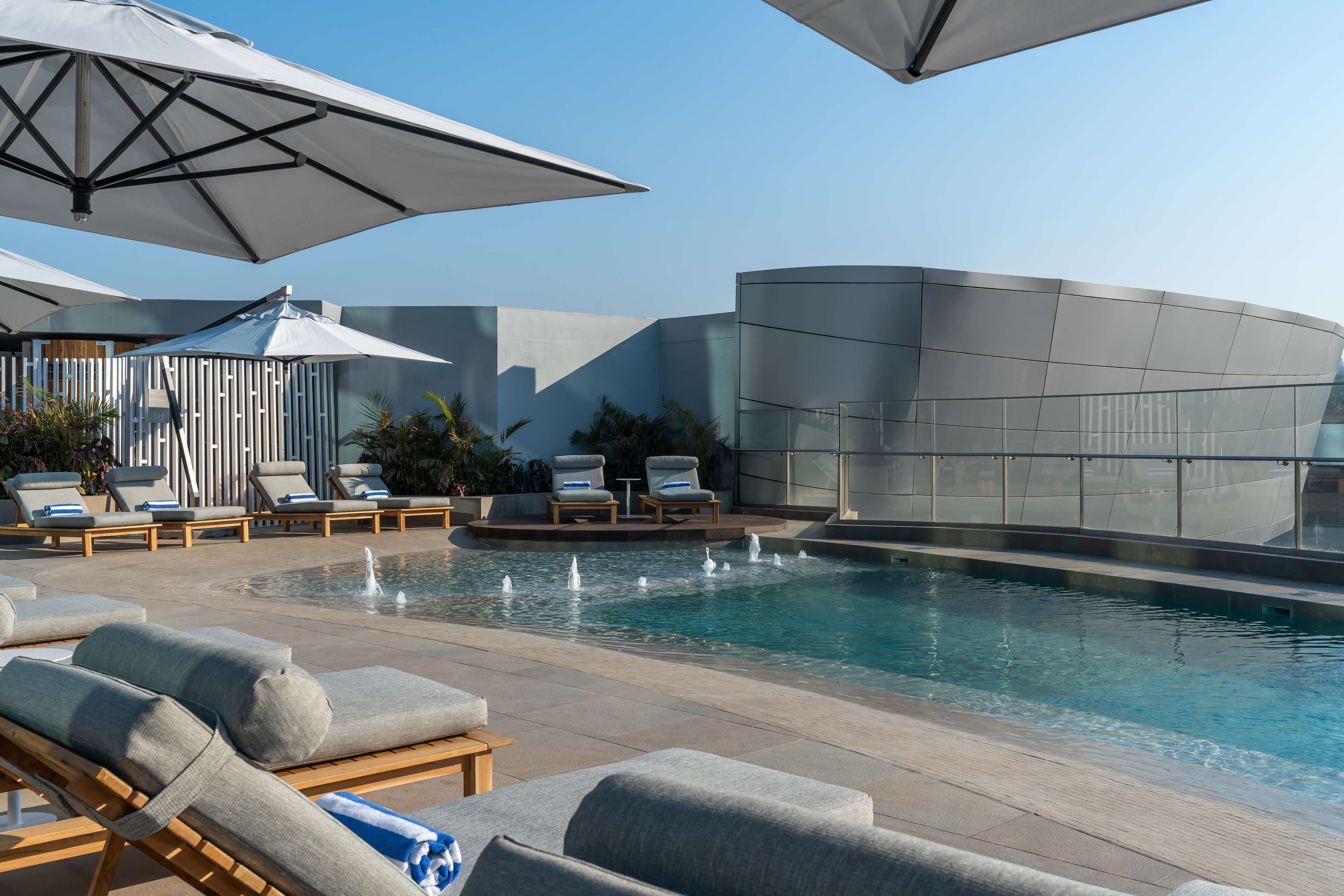 A modern pool area with lounge chairs and umbrellas.