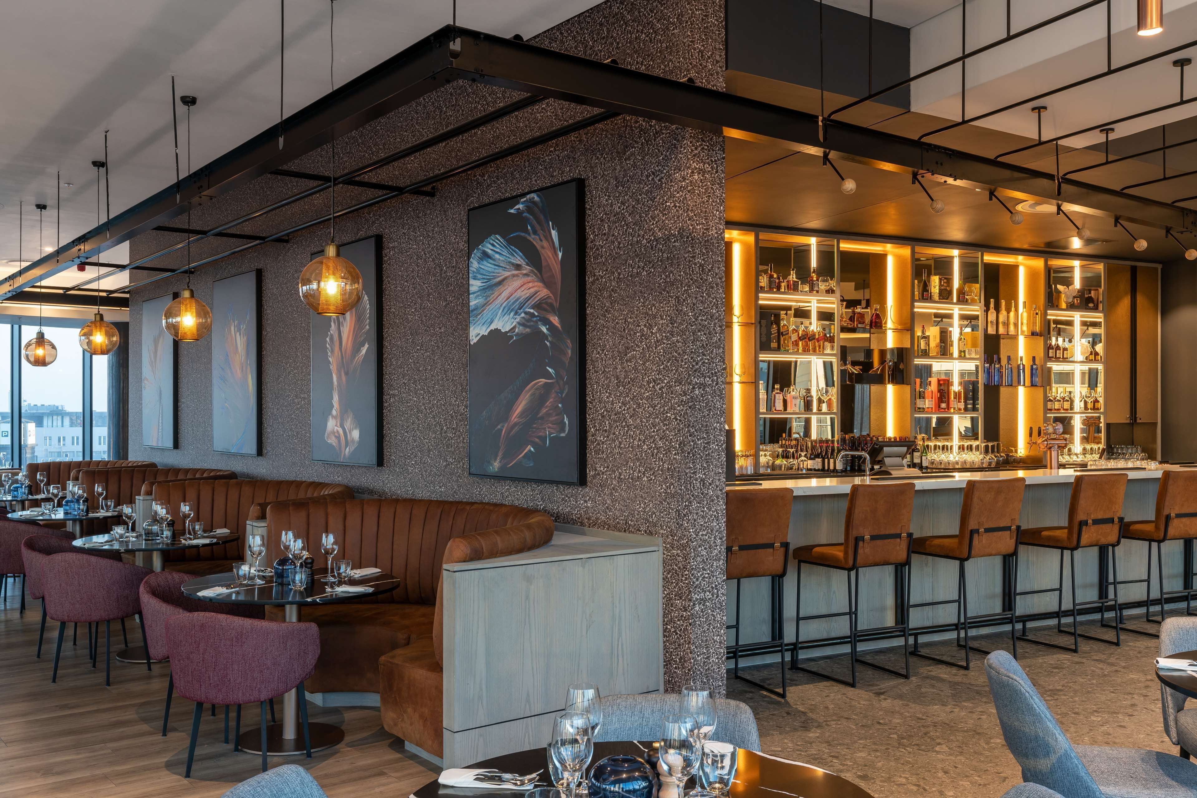 Un espace bar moderne, doté de sièges et d’un comptoir.
