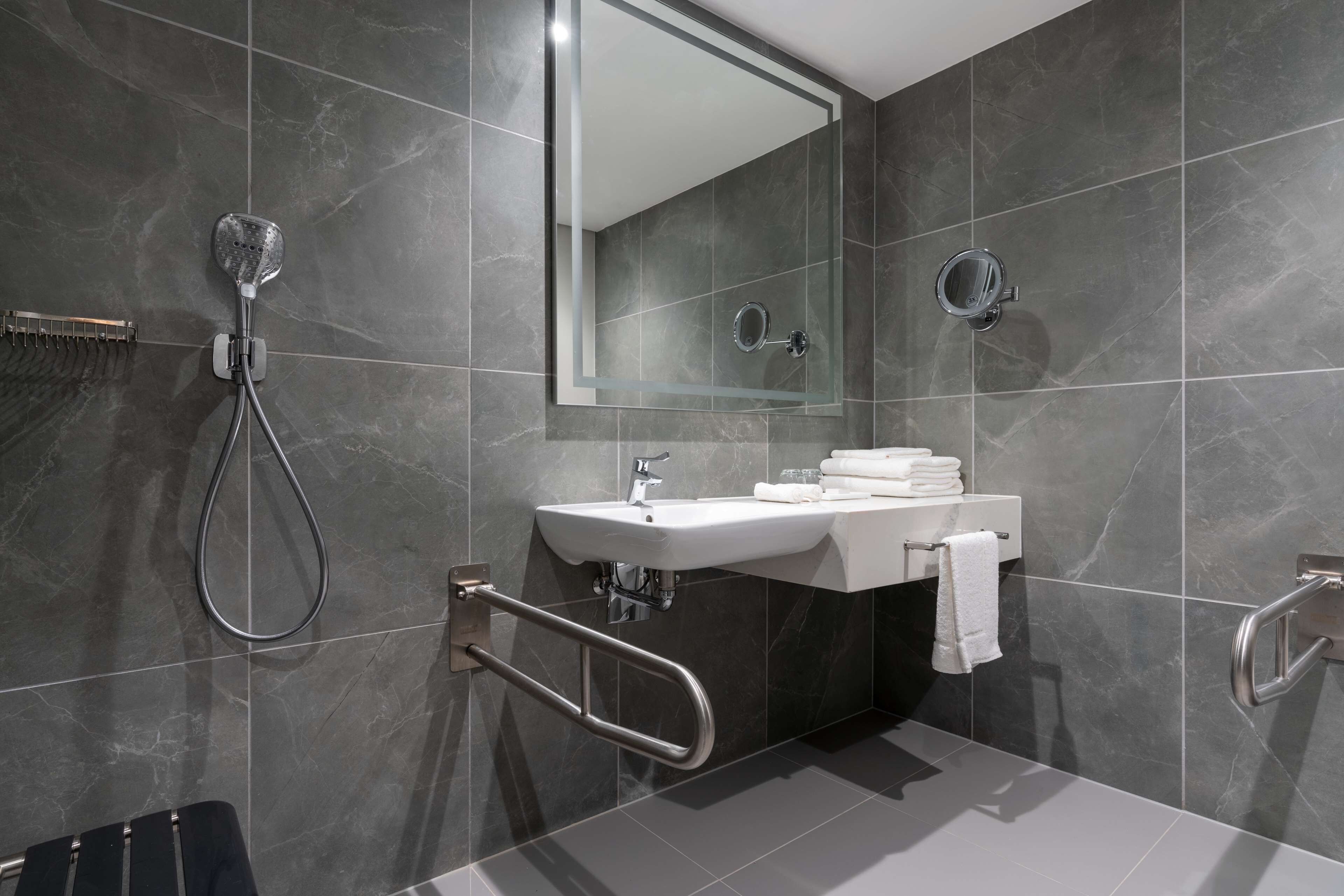 Een moderne badkamer met een wastafel, spiegel en douche.