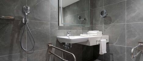 A modern bathroom with a sink, mirror, and shower.