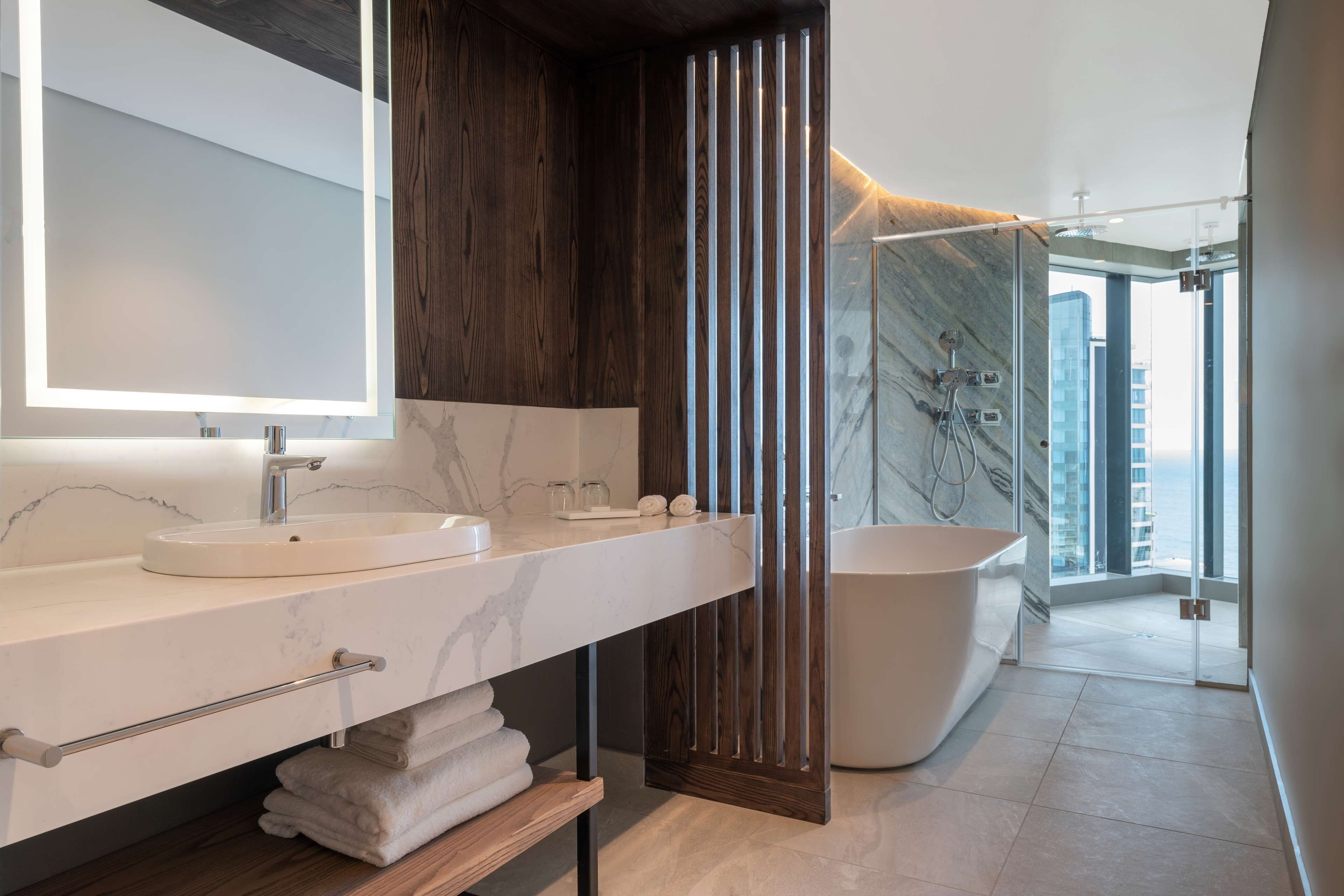 A modern bathroom with a large mirror, a sink, a bathtub, and a shower area.