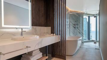 A modern bathroom with a large mirror, a sink, a bathtub, and a shower area.