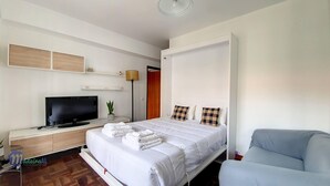 Ett hotellrum med en säng, en tv, ett skrivbord, en stol och en garderob.