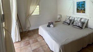 Un dormitorio con una cama grande, una ventana con cortinas, un cuadro en la pared y un techo de madera.