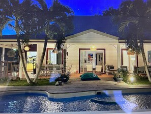 Ein Haus mit Swimmingpool, Palmen und Essbereich.
