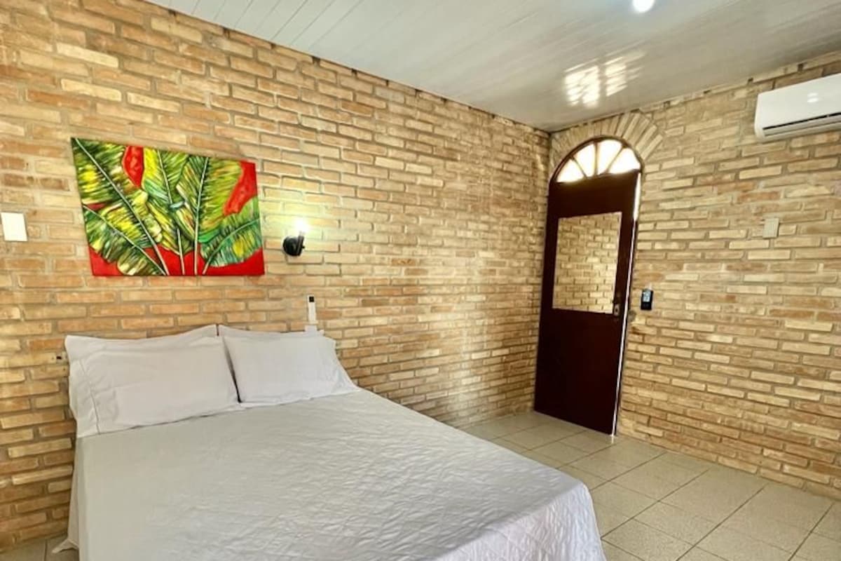 Ein Schlafzimmer mit einem Bett, einem Wandbild, einer Tür und einer Klimaanlage.