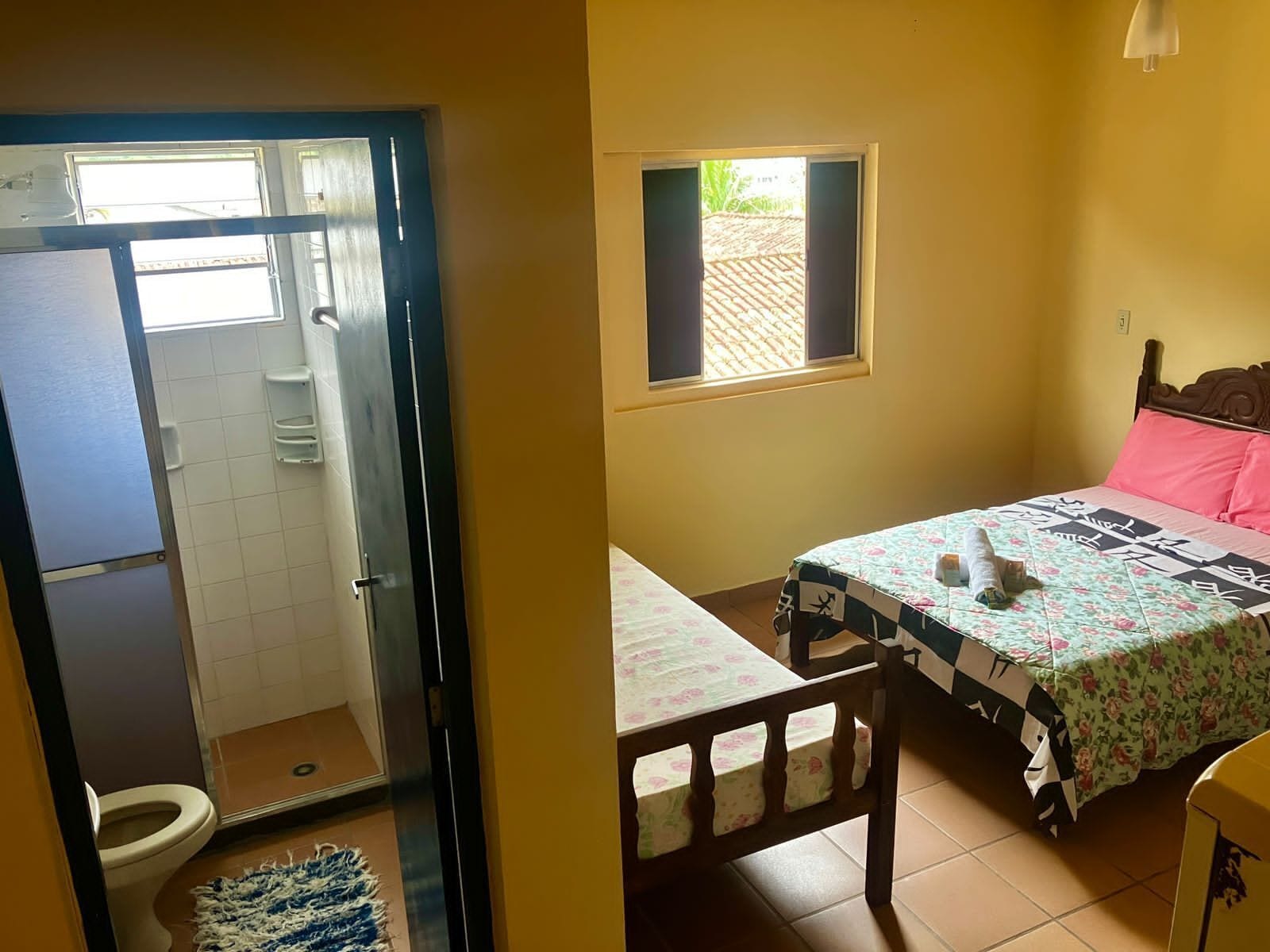 A bathroom with a toilet, shower, and a small rug.