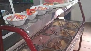 A buffet with various food items in glass containers, a red metal frame, and a tiled floor. - HOTEL NEVADA (Ubatuba)