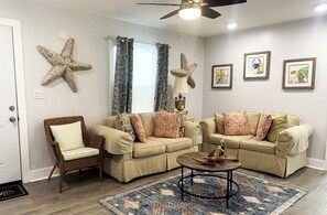 Relax in this inviting living room with two sofas, a wicker chair, and a coffee table.