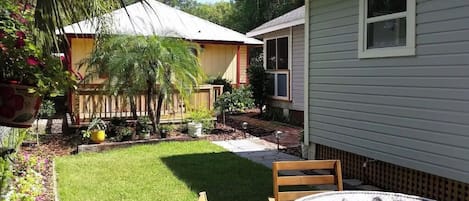A backyard with a lawn, a wooden deck, a small shed, and a house with a window.