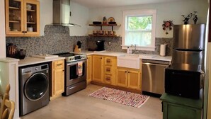 Una cocina moderna con armarios de madera, un refrigerador de acero inoxidable, horno empotrado y lavadora.