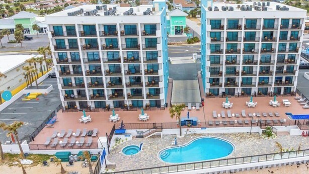 A hotel with multiple balconies, a pool area, and a view of the surrounding neighborhood. - Tropic Sun Towers (Ormond Beach)