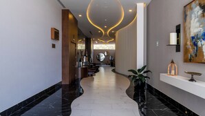 A modern hotel lobby with a curved marble floor, recessed lighting, and a large abstract painting on the wall. - Sheraton Guadalajara Expo (Zapopan)